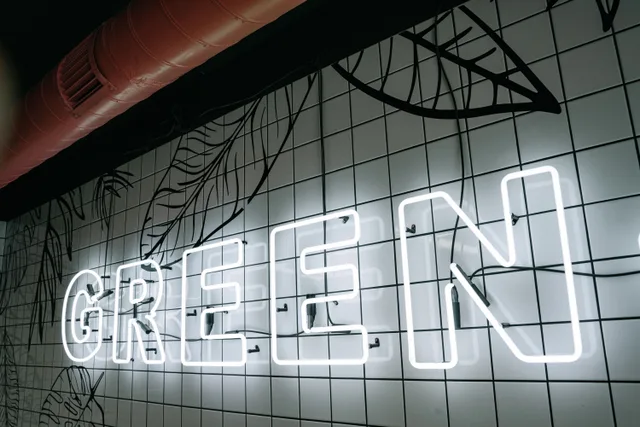 A neon sign spelling 'GREEN' on a tiled wall with a decorative design. The local search checklist for a sign shop owners