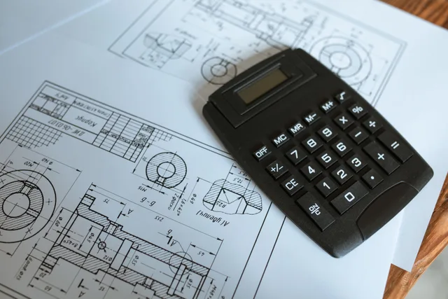 Close-up of a calculator resting on technical engineering blueprints, showcasing precise calculations. Making sense of sign shop operations and workflow
