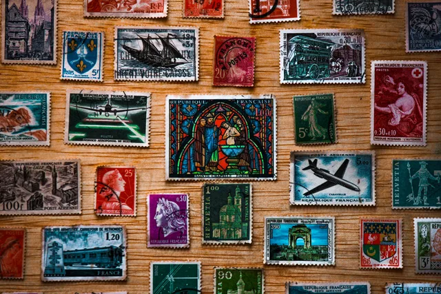 A collection of diverse vintage French postage stamps arranged on a wooden surface, showcasing history and art. Shipping signs to Canada: invoice, customs entry and French rules
