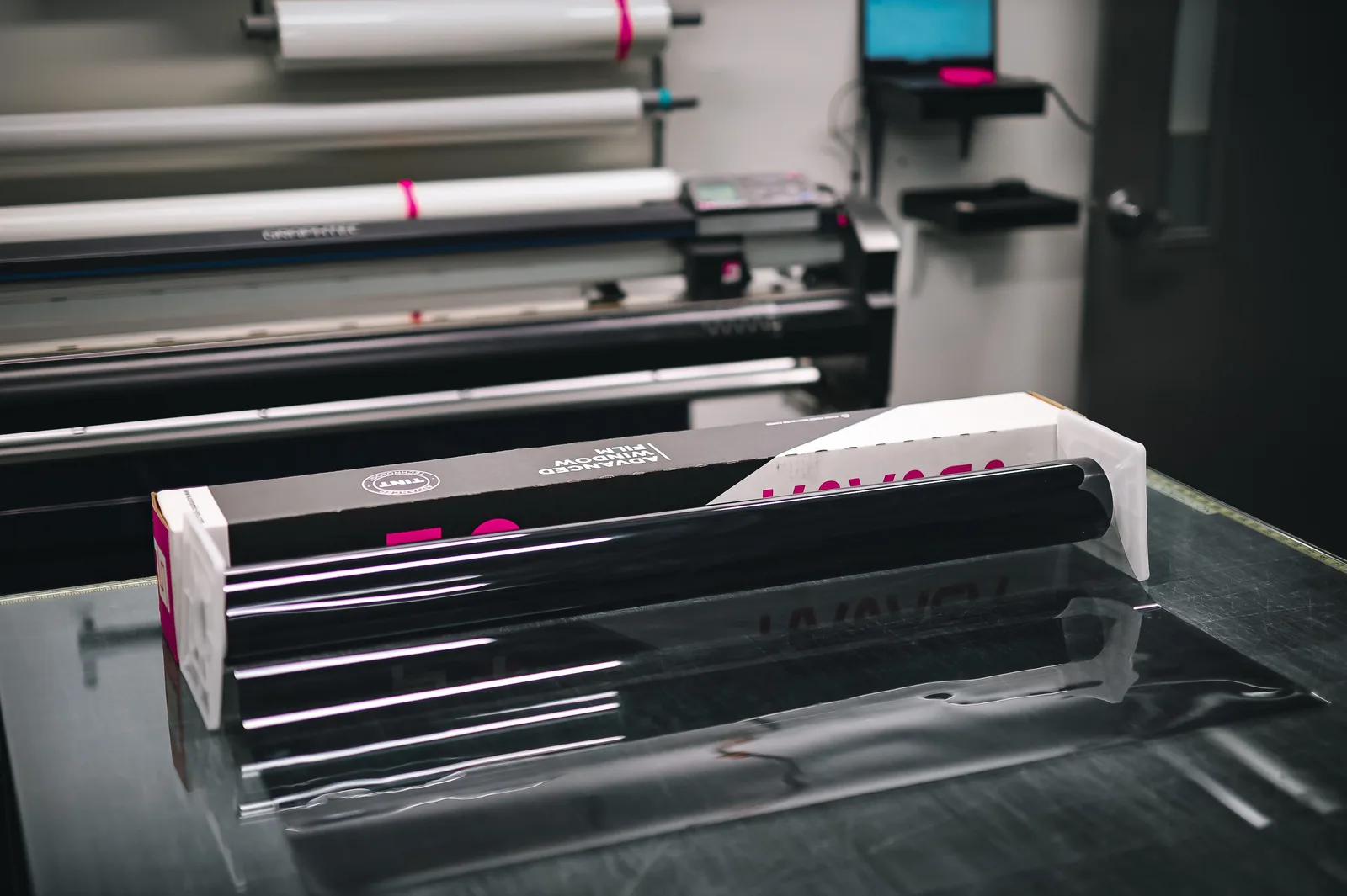 A glossy roll of vinyl material inside a modern print shop, ready for use in creating projects. Sign shop startup: when to hire your first installer