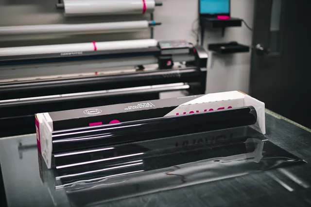 A glossy roll of vinyl material inside a modern print shop, ready for use in creating projects. Sign shop startup: when to hire your first installer